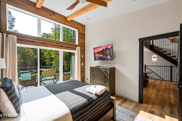 bedroom with beamed ceiling, hardwood / wood-style floors, access to outside, ceiling fan, and wooden walls