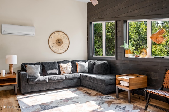 living room with a wall mounted AC, wood-type flooring, and wooden walls