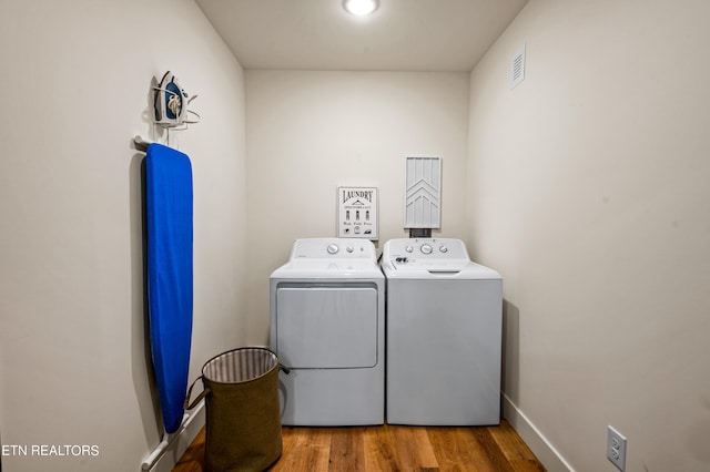 clothes washing area with hardwood / wood-style flooring and washing machine and dryer