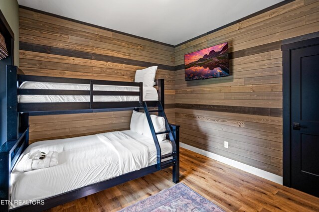 bedroom with hardwood / wood-style floors and wooden walls