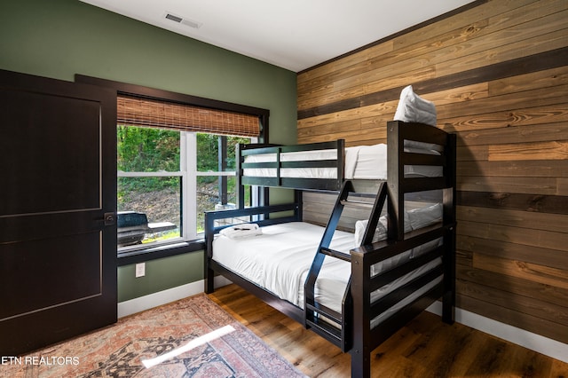 bedroom with wood-type flooring and wooden walls