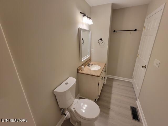 bathroom featuring wood-type flooring, toilet, and vanity