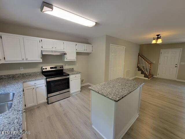 kitchen with electric range, light stone countertops, and white cabinets