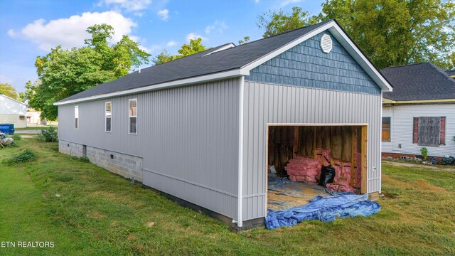 view of home's exterior with a garage, a lawn, and an outbuilding