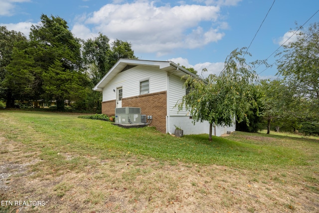 view of side of home featuring a yard and central AC