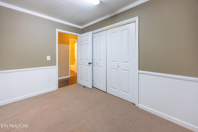 unfurnished bedroom with ornamental molding, a closet, and carpet floors