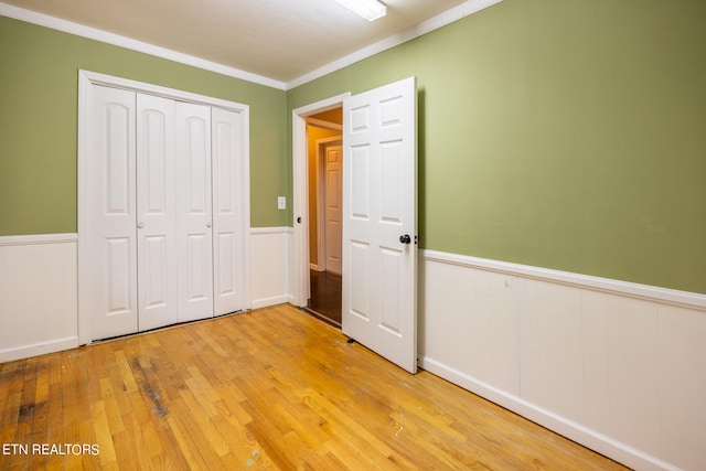 unfurnished bedroom with light hardwood / wood-style flooring, ornamental molding, and a closet