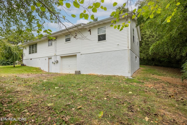 back of property with a garage and a lawn