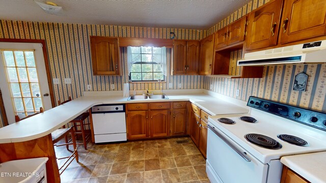 kitchen with white appliances, a textured ceiling, light tile patterned floors, kitchen peninsula, and sink