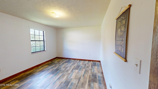 spare room with dark wood-type flooring and a textured ceiling