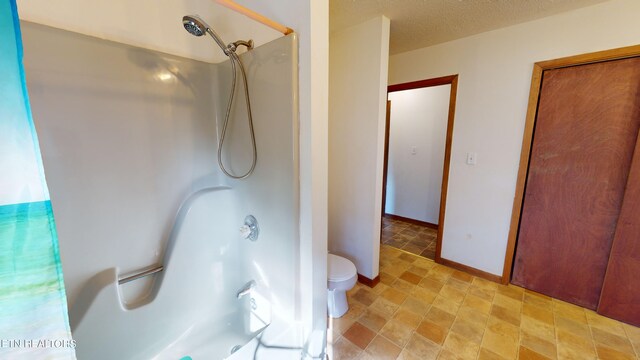 bathroom featuring a textured ceiling, toilet, and curtained shower