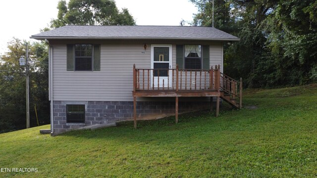 rear view of house with a lawn and a wooden deck