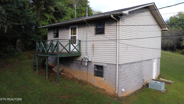 view of property exterior featuring cooling unit, a lawn, and a wooden deck