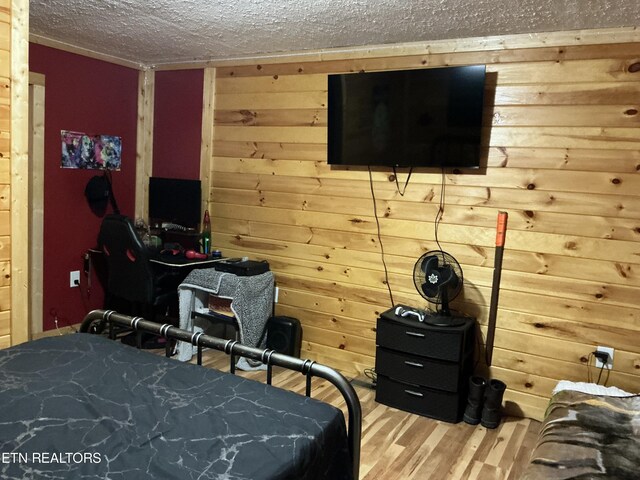 bedroom featuring wooden walls, hardwood / wood-style floors, and a textured ceiling