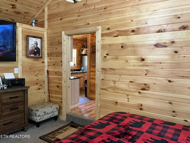 bedroom featuring carpet floors, wooden walls, and vaulted ceiling