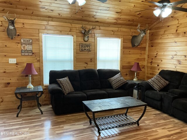 living room featuring wooden walls, wooden ceiling, light wood-type flooring, and ceiling fan