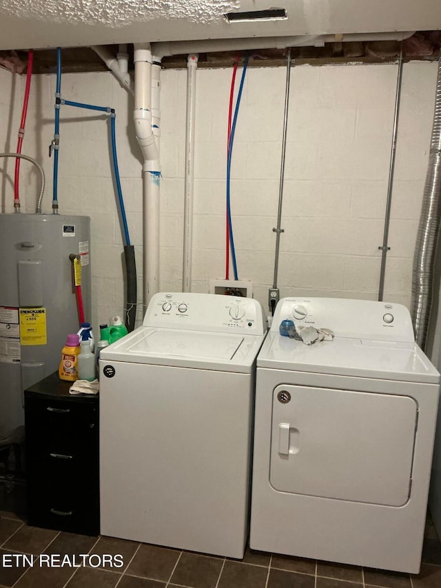 washroom with water heater, separate washer and dryer, and dark tile patterned flooring