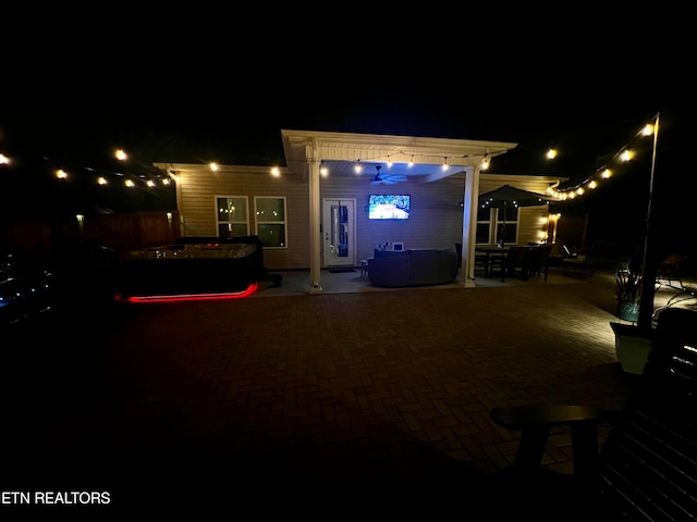 back house at night featuring a pergola and a patio