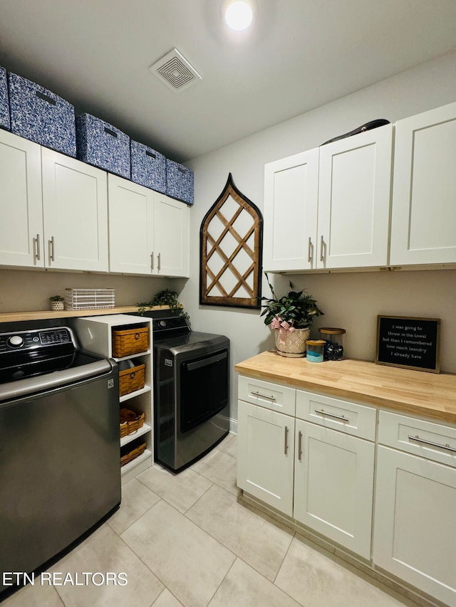 laundry room featuring cabinets, separate washer and dryer, and light tile patterned floors