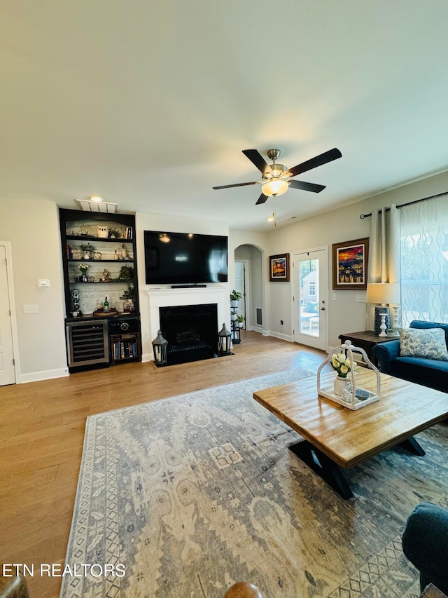 living room with ceiling fan, built in features, and light hardwood / wood-style flooring