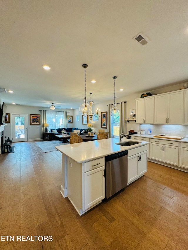 kitchen with dishwasher, light wood-type flooring, white cabinets, and a kitchen island with sink