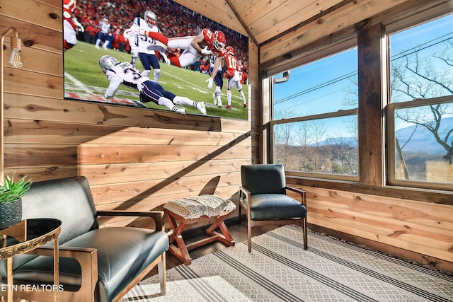 living area with vaulted ceiling and wooden walls