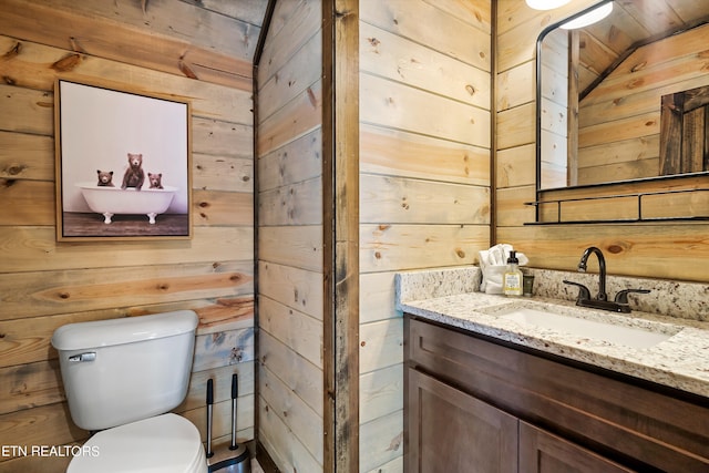 bathroom featuring wood walls, toilet, and vanity