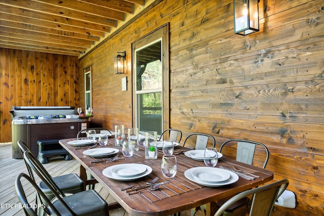 dining space featuring hardwood / wood-style floors, wood walls, and beam ceiling