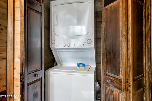 laundry room with wood walls and stacked washer and dryer