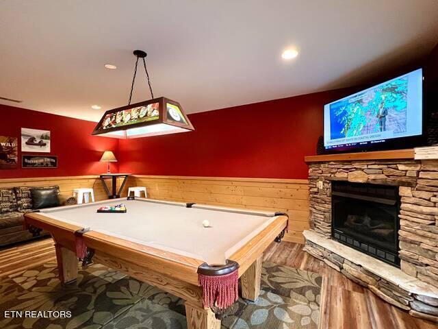 playroom featuring pool table, hardwood / wood-style flooring, and a stone fireplace