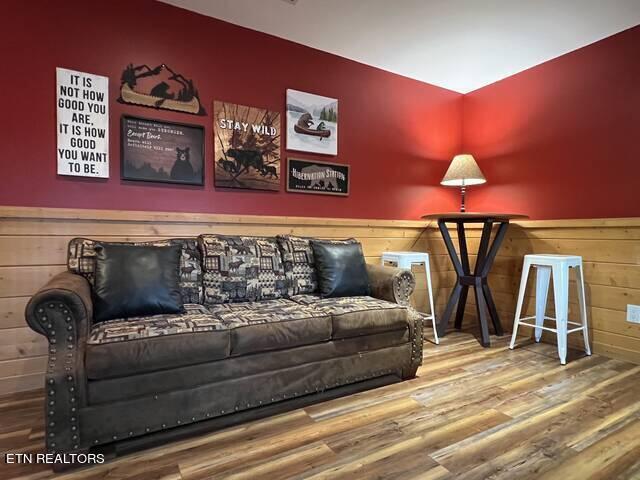 living room with hardwood / wood-style flooring and wood walls