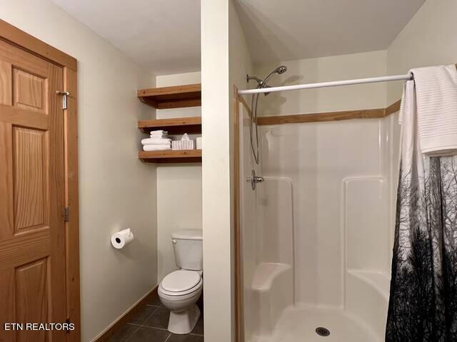 bathroom with toilet, tile patterned floors, and curtained shower