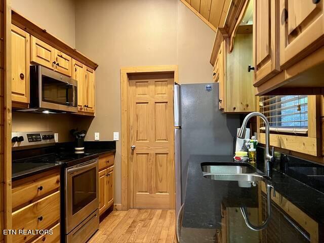 kitchen with sink, appliances with stainless steel finishes, wood ceiling, and light hardwood / wood-style flooring