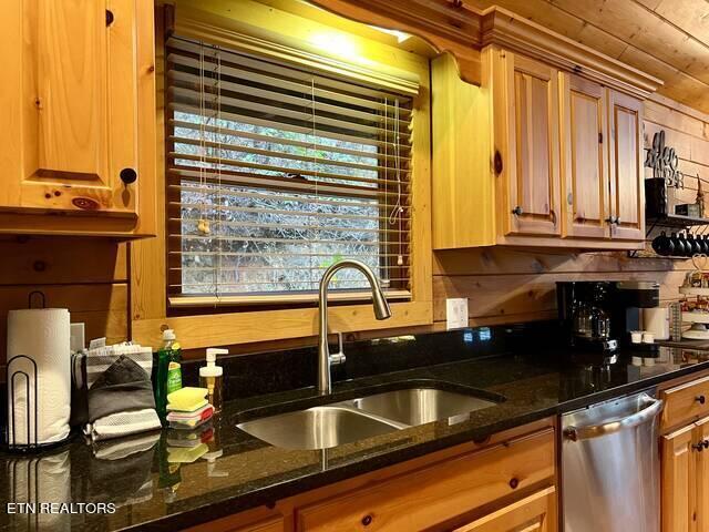 kitchen featuring dark stone countertops, sink, and stainless steel dishwasher