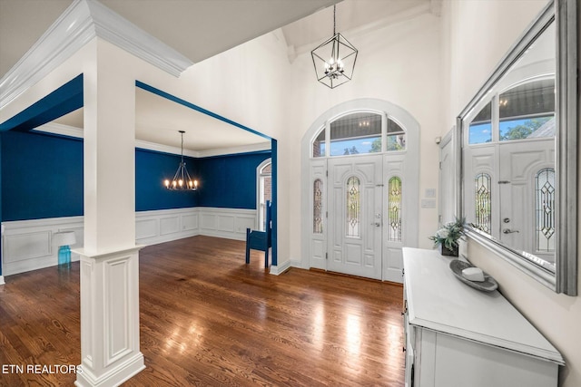 entrance foyer with an inviting chandelier, dark hardwood / wood-style floors, crown molding, and a wealth of natural light