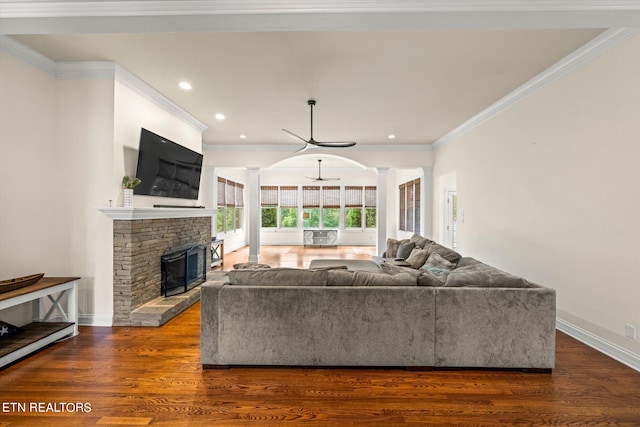 living room featuring crown molding, wood-type flooring, decorative columns, and a fireplace