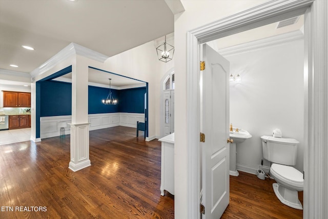 interior space featuring toilet, ornamental molding, hardwood / wood-style flooring, an inviting chandelier, and ornate columns