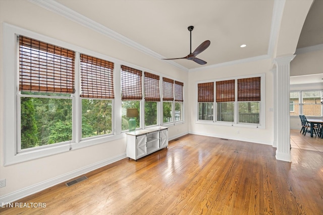 unfurnished sunroom with ornate columns, ceiling fan, and a wealth of natural light