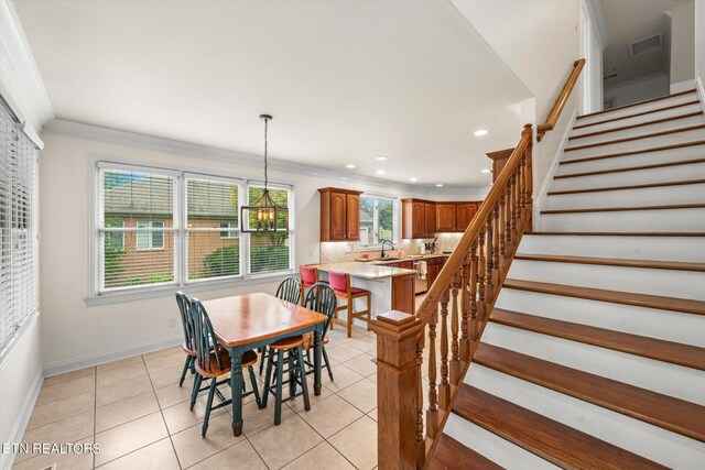 tiled dining space with a notable chandelier, crown molding, and sink