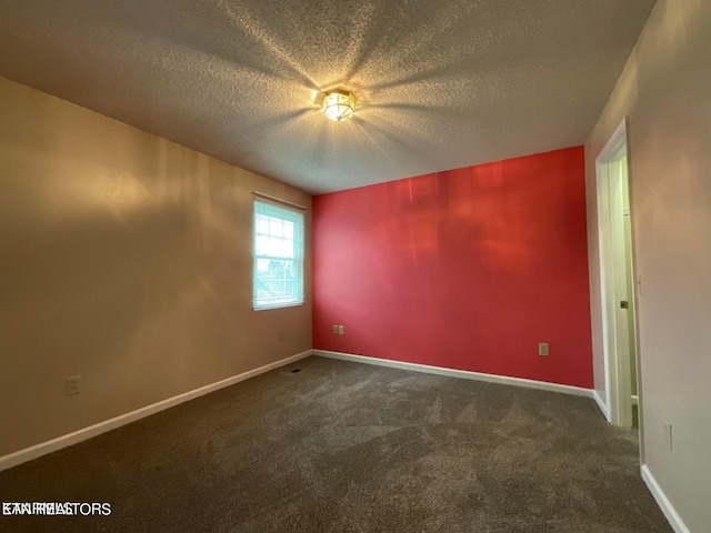 empty room featuring a textured ceiling and dark carpet