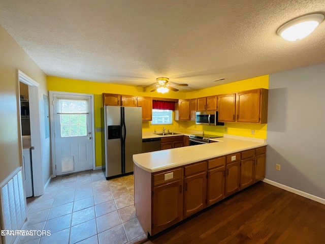 kitchen with a textured ceiling, appliances with stainless steel finishes, kitchen peninsula, sink, and ceiling fan