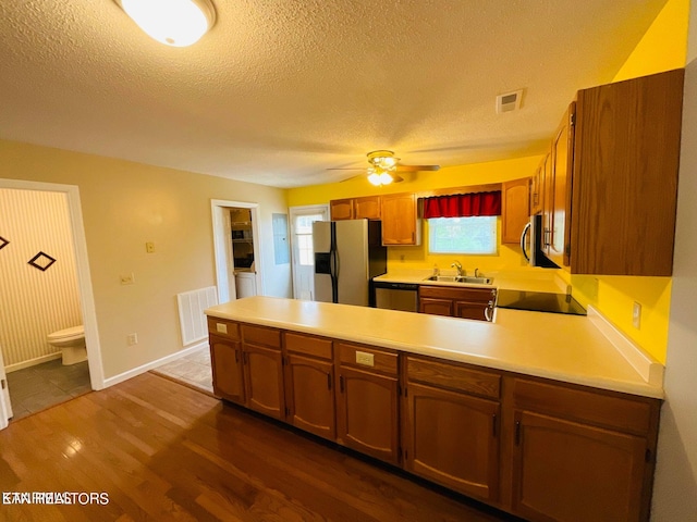 kitchen featuring hardwood / wood-style floors, a textured ceiling, stainless steel appliances, sink, and ceiling fan