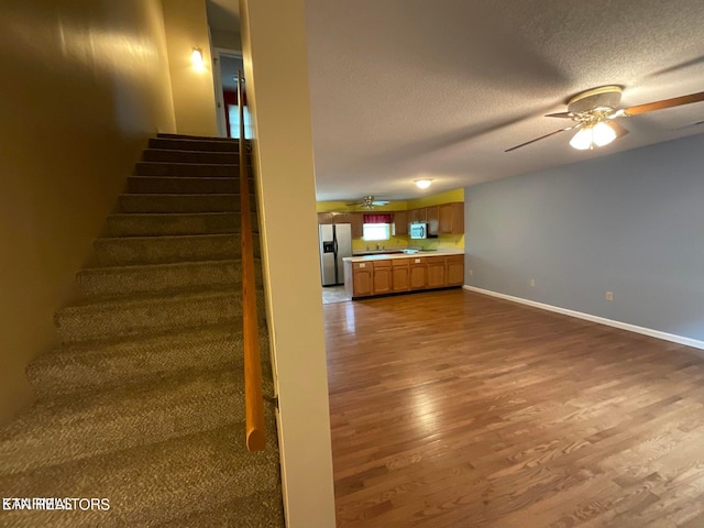 staircase with wood-type flooring, a textured ceiling, and ceiling fan