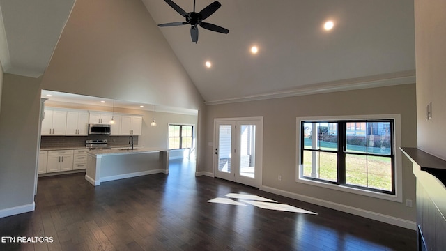 unfurnished living room with high vaulted ceiling, ceiling fan, dark wood-type flooring, and sink