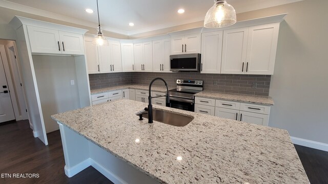 kitchen featuring appliances with stainless steel finishes, decorative light fixtures, white cabinetry, and sink