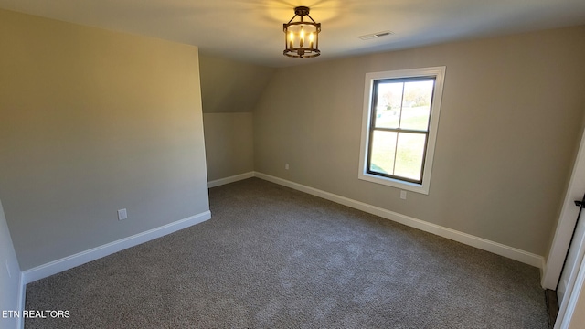 bonus room with dark colored carpet and lofted ceiling