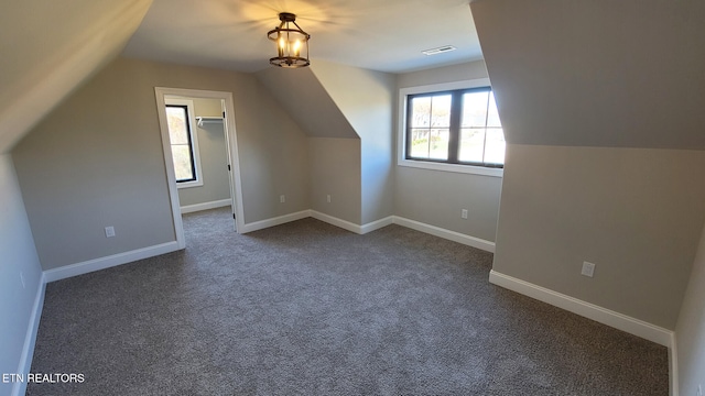 bonus room with dark colored carpet and vaulted ceiling