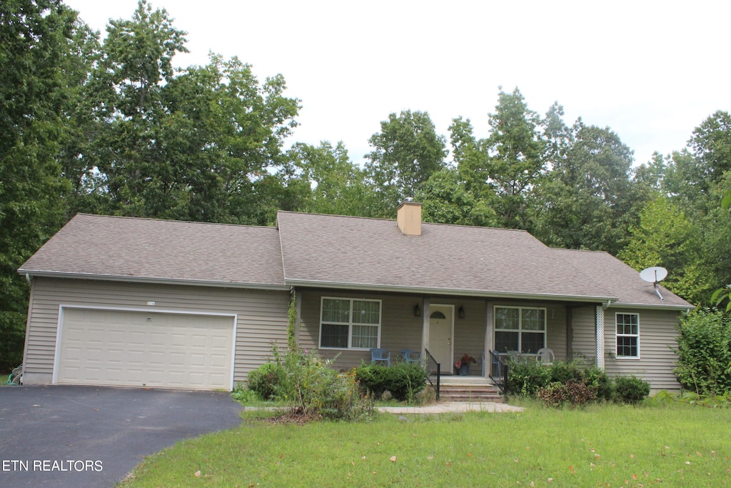 ranch-style house with covered porch, a front yard, and a garage