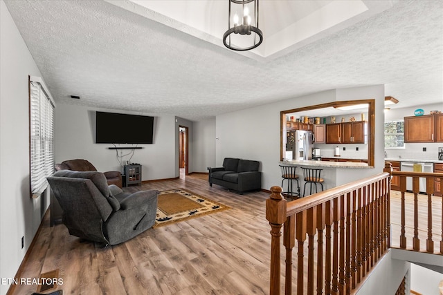 living room featuring a textured ceiling, an inviting chandelier, and light hardwood / wood-style floors