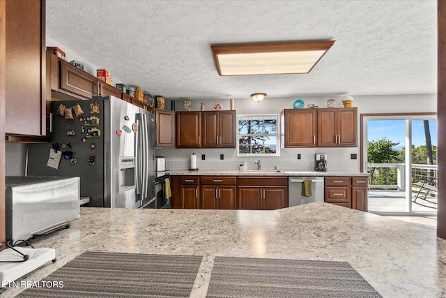 kitchen with a textured ceiling, backsplash, stainless steel appliances, sink, and kitchen peninsula